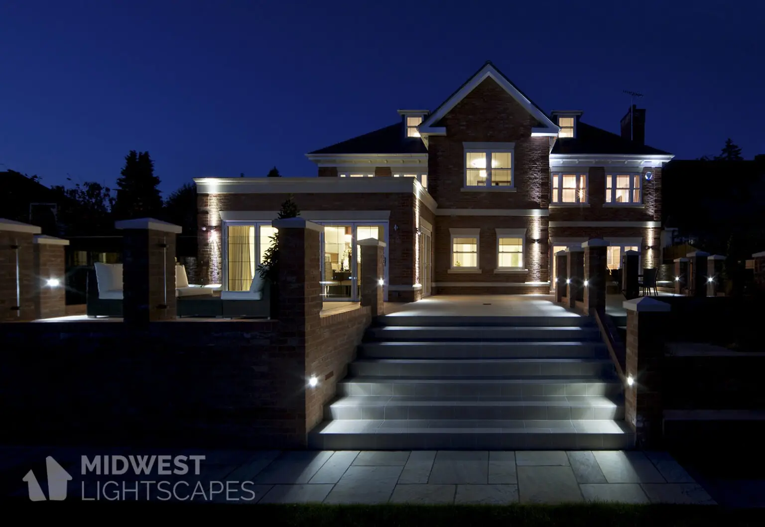 Illuminated brick home with uplights, path lights along stairs and walkway | Midwest Lightscapes, Kankakee, Illinois
